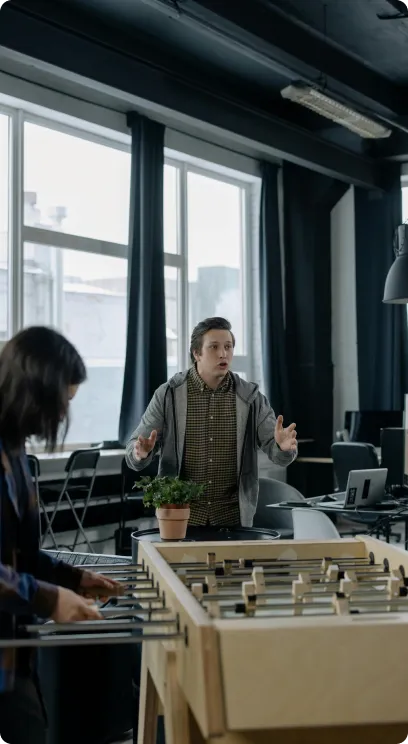 Two people playing foosball in a modern office